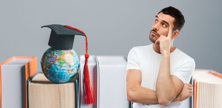 Knjige i globus s kapom uz muškarca koji razmišlja